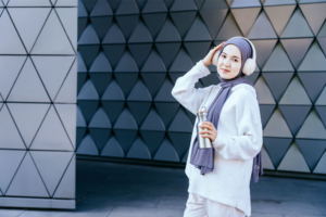 Wanita menggunakan headphone dengan gaya fashion hijab yang terlihat modis