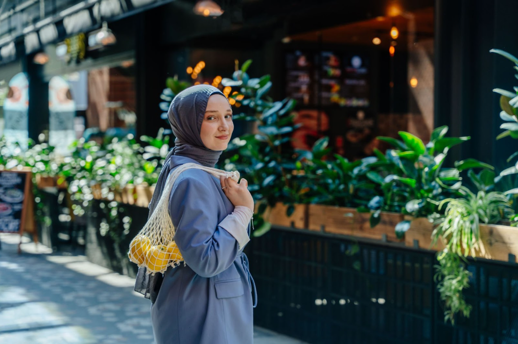 Wanita berhijab di depan cafe membawa buah-buahan